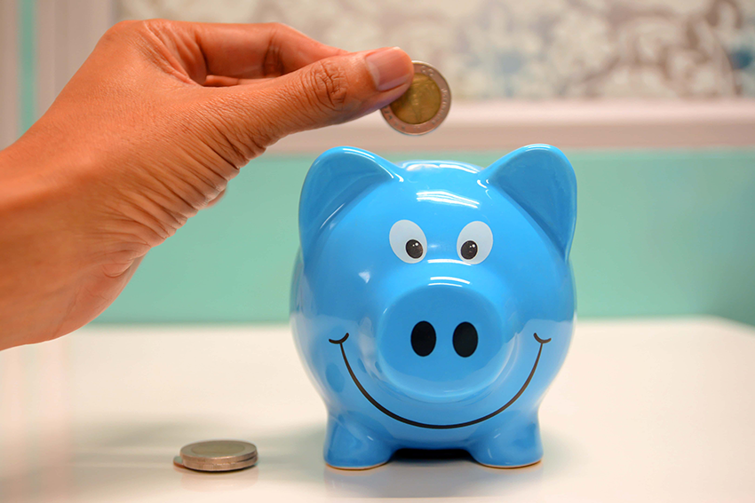 Picture of a person putting a coin to save in a blue piggy bank