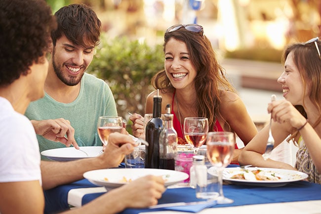 Picture of several friends eating out but not realizing that they should focus on how to stop eating out to save money